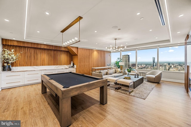 game room with wood walls, a chandelier, a tray ceiling, billiards, and light hardwood / wood-style floors