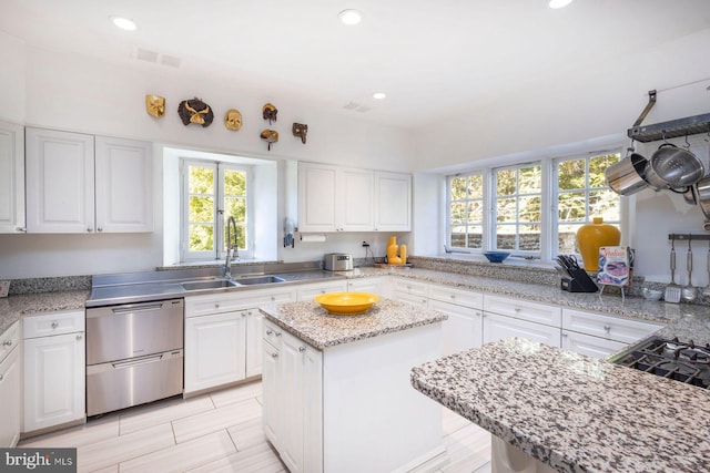 kitchen with white cabinets, dishwasher, sink, and a center island