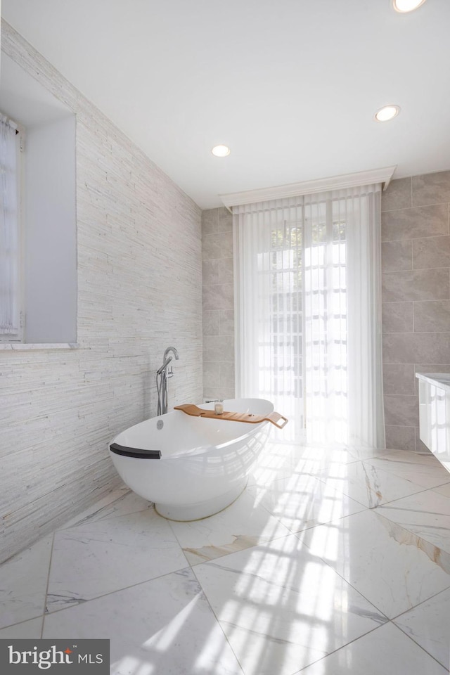 bathroom featuring tile walls and a washtub