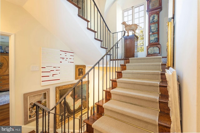 stairway featuring wood-type flooring and high vaulted ceiling