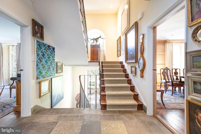 staircase featuring hardwood / wood-style flooring, ornamental molding, and a healthy amount of sunlight