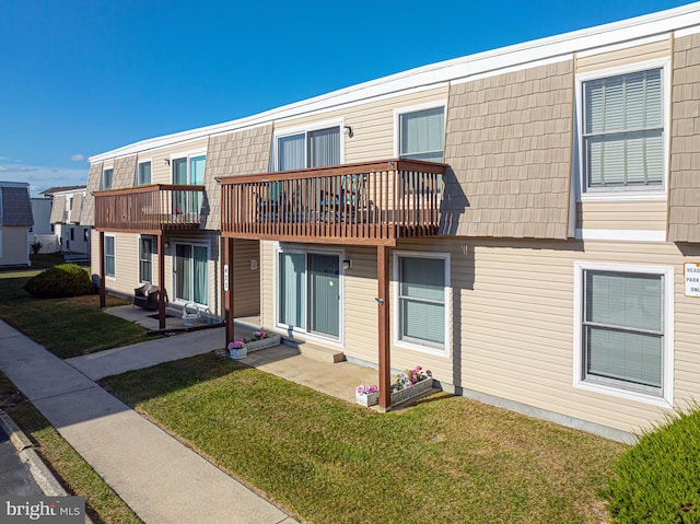 rear view of house featuring a patio area, a yard, and a balcony