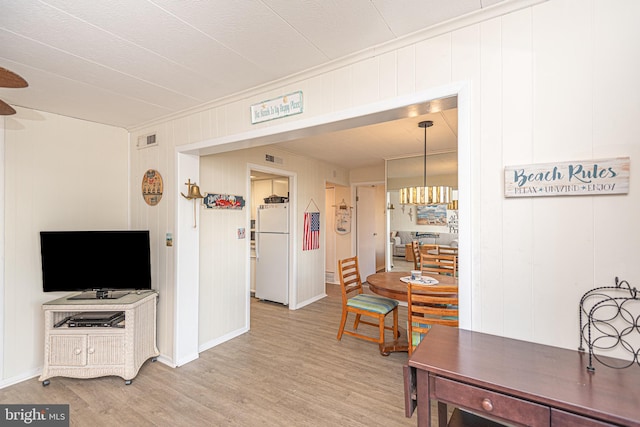 dining room featuring wood walls, an inviting chandelier, and hardwood / wood-style flooring