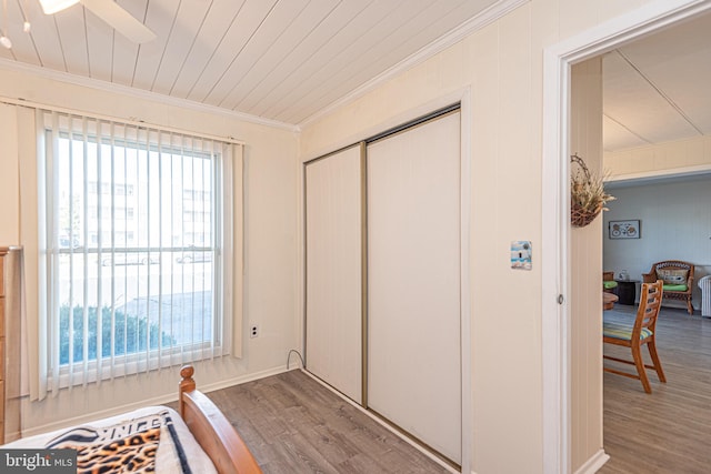 bedroom with hardwood / wood-style flooring, ceiling fan, crown molding, and a closet