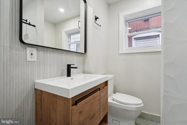 bathroom with a healthy amount of sunlight, backsplash, vanity, and toilet