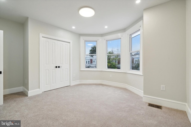 unfurnished bedroom featuring light carpet and a closet