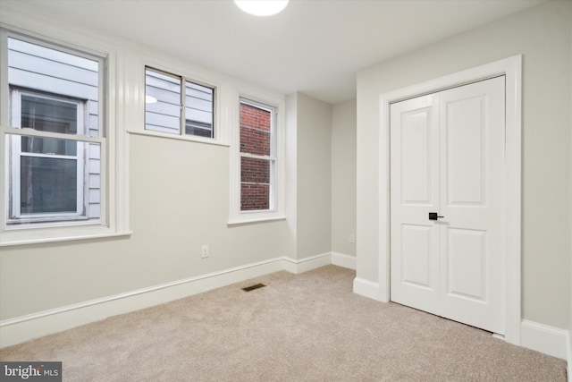 unfurnished bedroom featuring light colored carpet and a closet