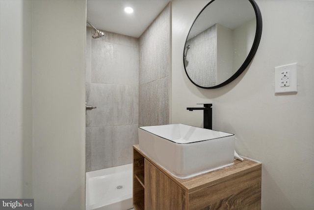 bathroom featuring tiled shower and vanity