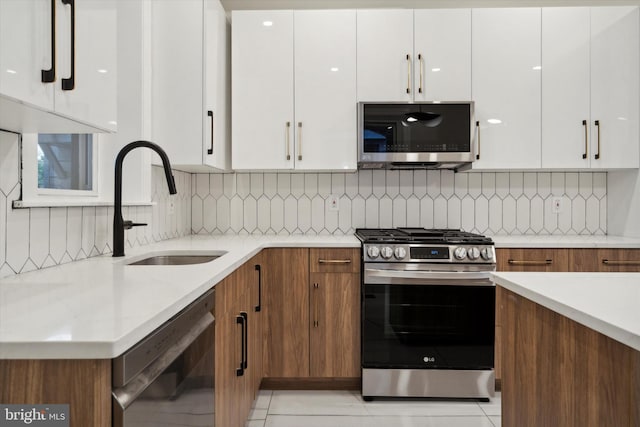 kitchen with backsplash, white cabinetry, light tile patterned floors, and stainless steel appliances