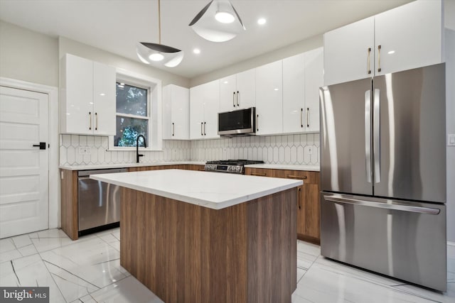 kitchen with a center island, sink, white cabinets, decorative backsplash, and stainless steel appliances