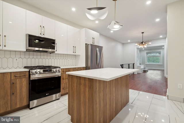 kitchen featuring white cabinets, pendant lighting, stainless steel appliances, a center island, and light hardwood / wood-style flooring