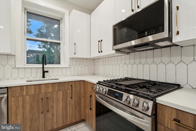 kitchen featuring decorative backsplash, white cabinetry, sink, and stainless steel appliances