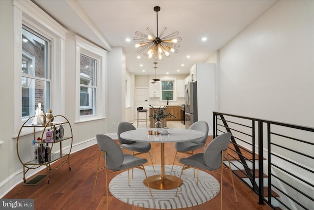 dining space featuring a healthy amount of sunlight, an inviting chandelier, dark wood-type flooring, and sink