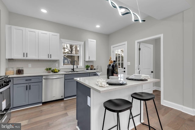 kitchen featuring white cabinetry, a kitchen island, gray cabinets, stainless steel dishwasher, and sink