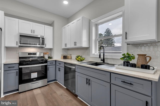 kitchen with gray cabinetry, wood-type flooring, appliances with stainless steel finishes, and sink