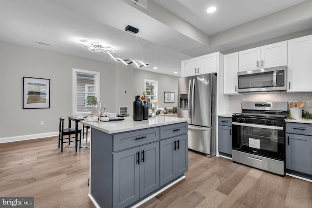 kitchen with gray cabinetry, stainless steel appliances, white cabinetry, and light wood-type flooring