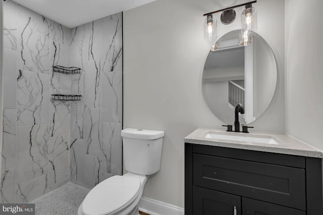 bathroom with tiled shower, vanity, and toilet