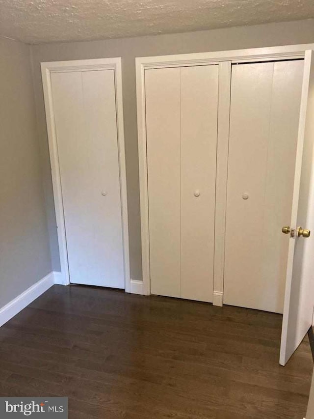 unfurnished bedroom with a textured ceiling and dark hardwood / wood-style flooring