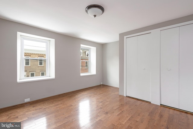 unfurnished bedroom featuring multiple closets and light hardwood / wood-style flooring