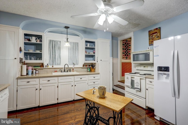 kitchen featuring dark wood-type flooring, white appliances, pendant lighting, ceiling fan, and sink