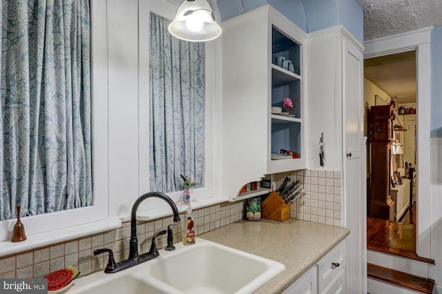 kitchen featuring light stone counters, sink, decorative backsplash, and white cabinetry