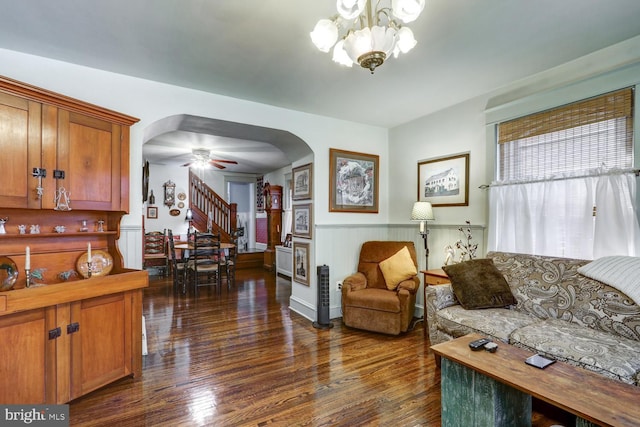 living room with ceiling fan with notable chandelier and dark hardwood / wood-style floors