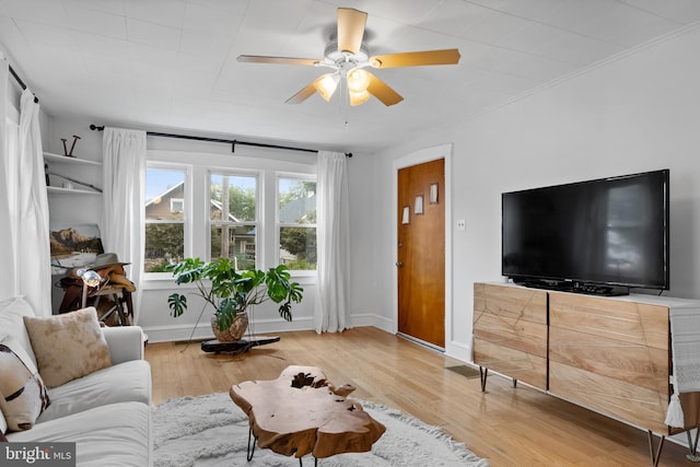 living room featuring ceiling fan, hardwood / wood-style flooring, and crown molding