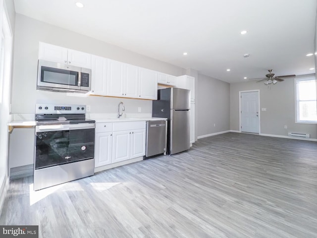 kitchen with appliances with stainless steel finishes, white cabinetry, ceiling fan, light hardwood / wood-style flooring, and sink