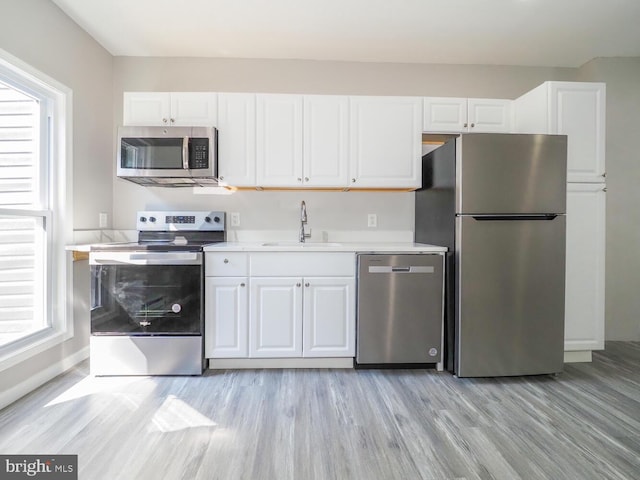 kitchen with appliances with stainless steel finishes, sink, light hardwood / wood-style flooring, and plenty of natural light