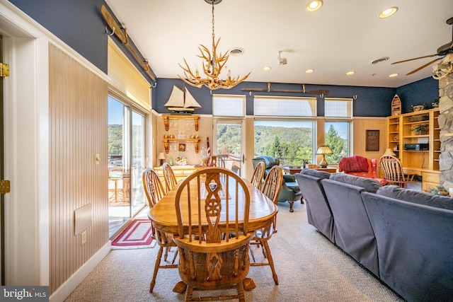 dining area featuring ceiling fan with notable chandelier and carpet flooring