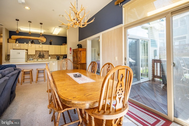 carpeted dining area with a healthy amount of sunlight and a notable chandelier