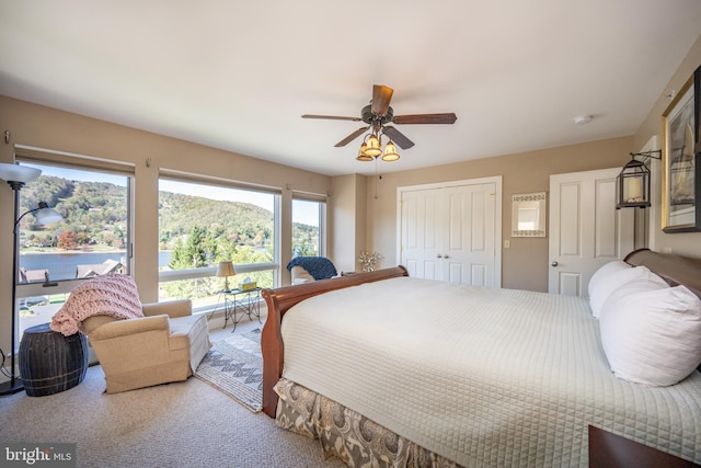 carpeted bedroom with ceiling fan, a mountain view, and a closet