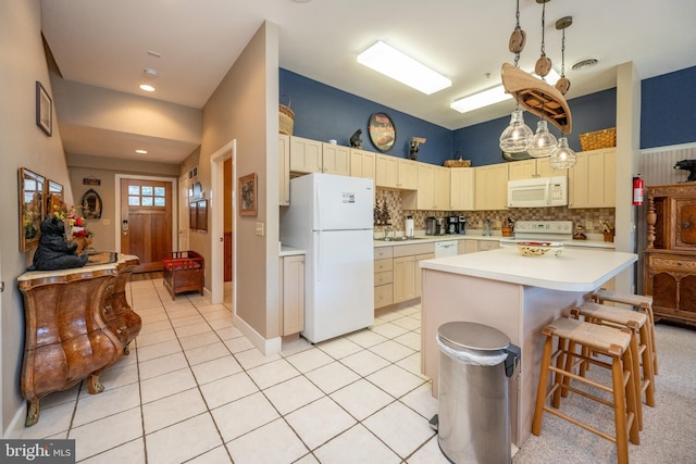 kitchen with light tile patterned flooring, white appliances, decorative light fixtures, a center island, and a breakfast bar area