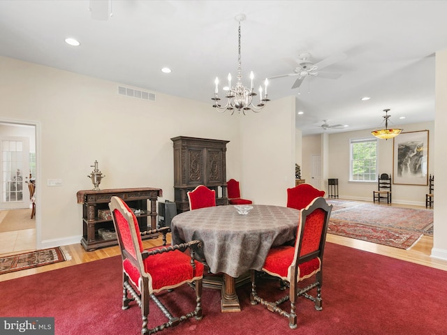 dining room with ceiling fan with notable chandelier and hardwood / wood-style flooring