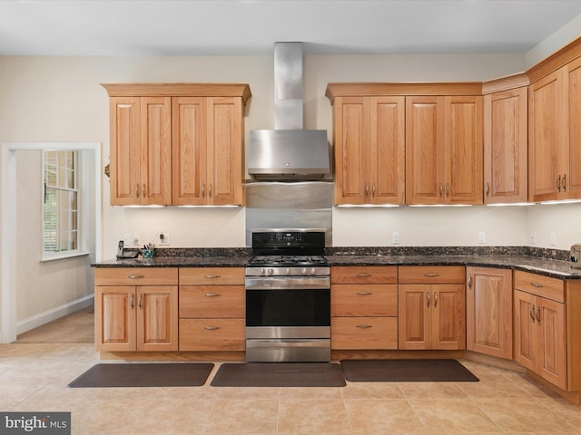 kitchen with dark stone countertops, wall chimney exhaust hood, and stainless steel gas range