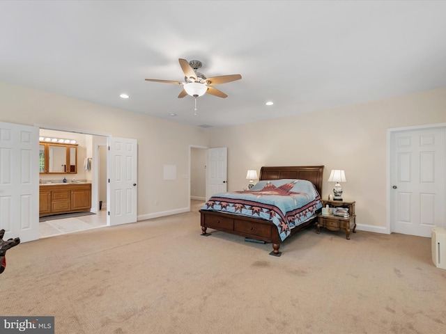 bedroom featuring light carpet, ensuite bathroom, and ceiling fan