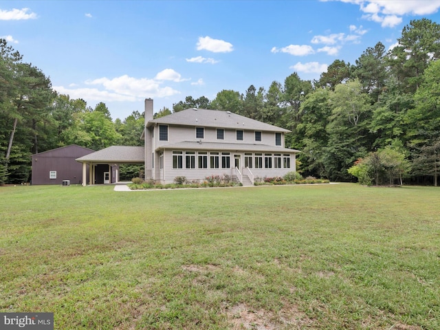 rear view of house with a sunroom, a yard, and a carport