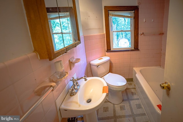 bathroom with a bathtub, tile walls, tile patterned flooring, toilet, and sink