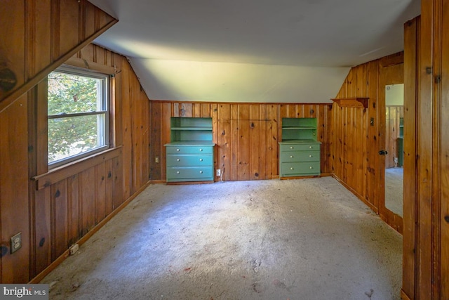 additional living space featuring lofted ceiling and wooden walls