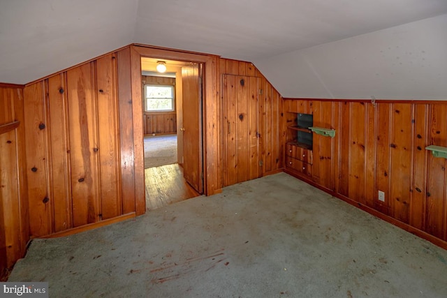 additional living space featuring light carpet, wooden walls, and vaulted ceiling