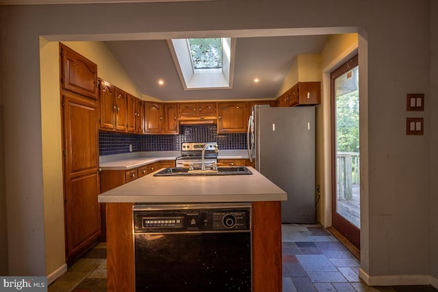 kitchen featuring appliances with stainless steel finishes, decorative backsplash, an island with sink, lofted ceiling with skylight, and sink