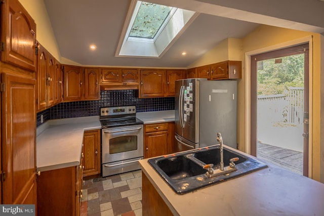 kitchen featuring vaulted ceiling with skylight, appliances with stainless steel finishes, tasteful backsplash, and sink