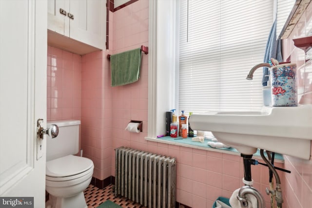 bathroom with toilet, radiator, tile patterned floors, sink, and tile walls