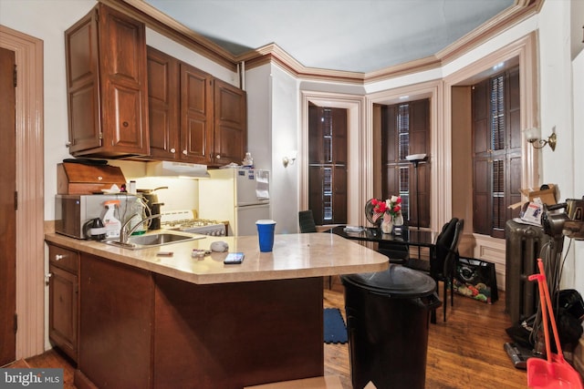 kitchen with ornamental molding, kitchen peninsula, white fridge, a breakfast bar area, and dark hardwood / wood-style flooring