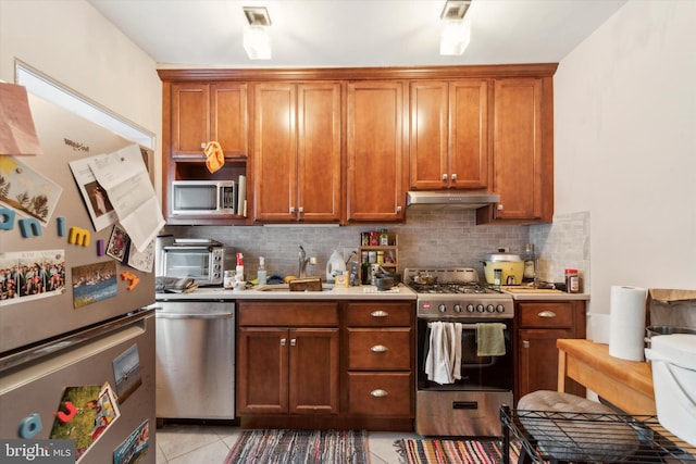 kitchen with stainless steel appliances, backsplash, sink, and light tile patterned floors