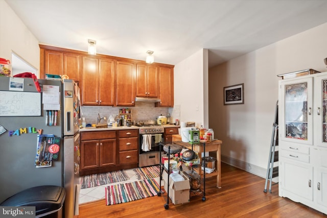 kitchen featuring appliances with stainless steel finishes, hardwood / wood-style flooring, sink, and backsplash