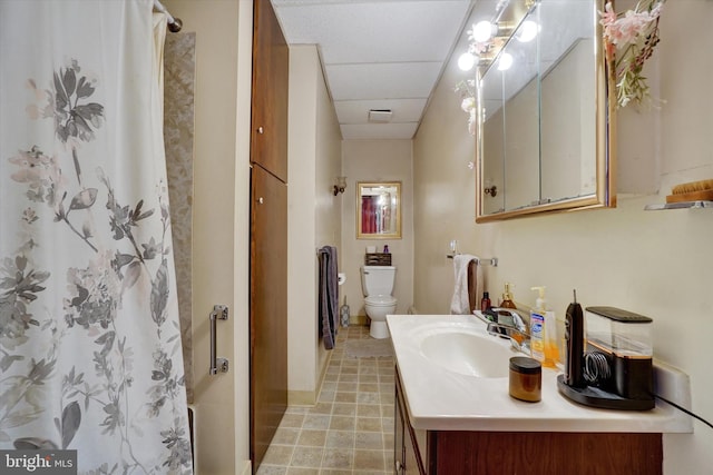 bathroom with a paneled ceiling, vanity, tile patterned flooring, toilet, and curtained shower