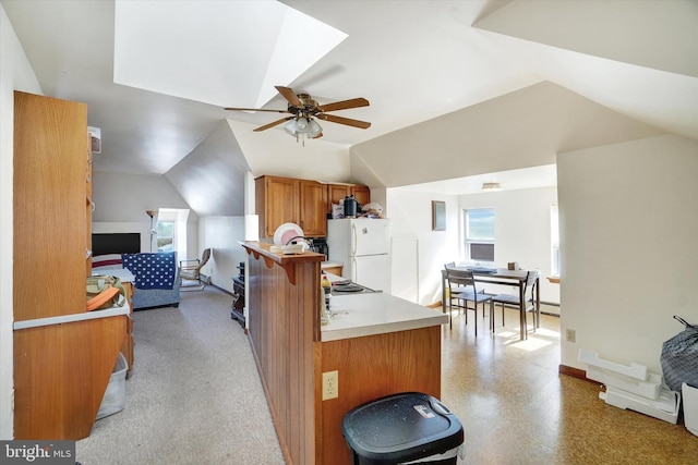 kitchen featuring ceiling fan, white refrigerator, lofted ceiling, and kitchen peninsula