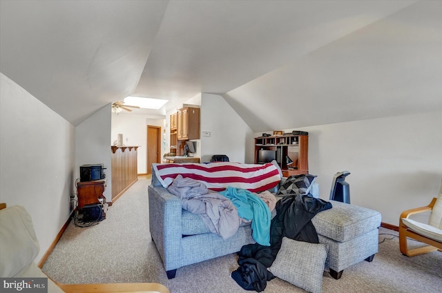 interior space featuring ceiling fan, vaulted ceiling with skylight, and light colored carpet