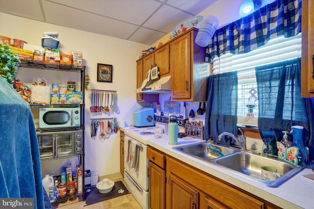 kitchen with a drop ceiling, light tile patterned floors, white appliances, and sink